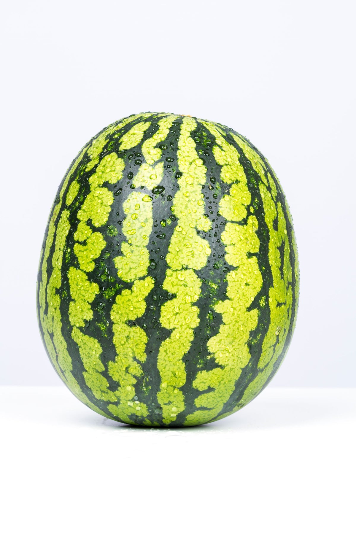 Dark green striped watermelon (Citrullus lanatus), whole fruit — is variety ka round-oval shape aur classic dark-green stripe pattern